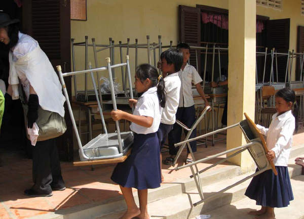 机・イスの搬入をお手伝いする小学生